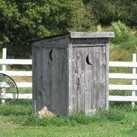 An outhouse on a field of green grass